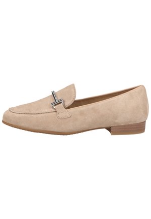Beige suède instappers met een ronde neus, decoratieve zilveren hardware op de voorkant en een lage bruine rubberen hak. Gladde textuur overal.