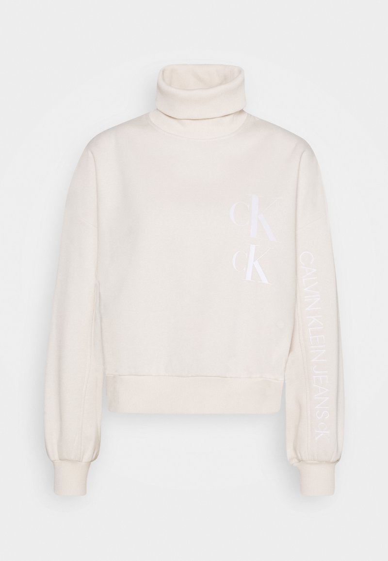 Krémový rolákový svetr s bílým logem Calvin Klein Jeans na přední straně a na rukávu, s žebrovanými manžetami a spodním lemem.