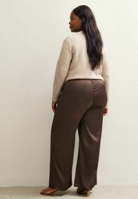 Brown satin wide-leg trousers paired with a beige sweater, featuring ribbed cuffs and a simple design. Model viewed from the back.