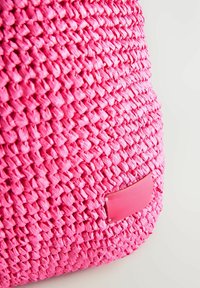 Szövéssel készült pink táska, texturált anyagból, sima bőrpanelekkel. Sűrű kivitel és élénk szín jellemzi.