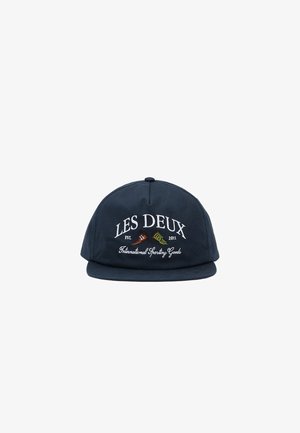 Tumesinine puuvillane nokamüts, millel on lamelipp. Kaunistatud tikitud tekstiga ja kahe ristatud ikooniga, millel on sildid "LES DEUX" ja "International Sporting Goods".