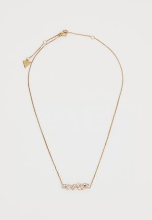 Gouden ketting met meerdere heldere edelstenen in verschillende vormen, tegen een slanke, dunne ketting met een słuitsluiting.