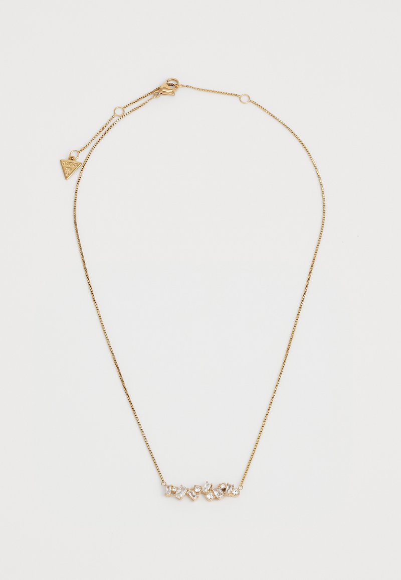 Gouden ketting met meerdere heldere edelstenen in verschillende vormen, tegen een slanke, dunne ketting met een słuitsluiting.