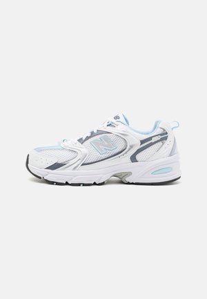 Weißer und hellblauer New Balance Laufschuh mit Mesh- und synthetischem Obermaterial, dicker Sohle und Schnürverschluss, seitlich gezeigt.