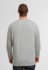 Maglione grigio a maglia con maniche lunghe, colletto rotondo, polsini e orlo a coste. Tessuto testurizzato con un motivo sottile. Parte posteriore semplice.