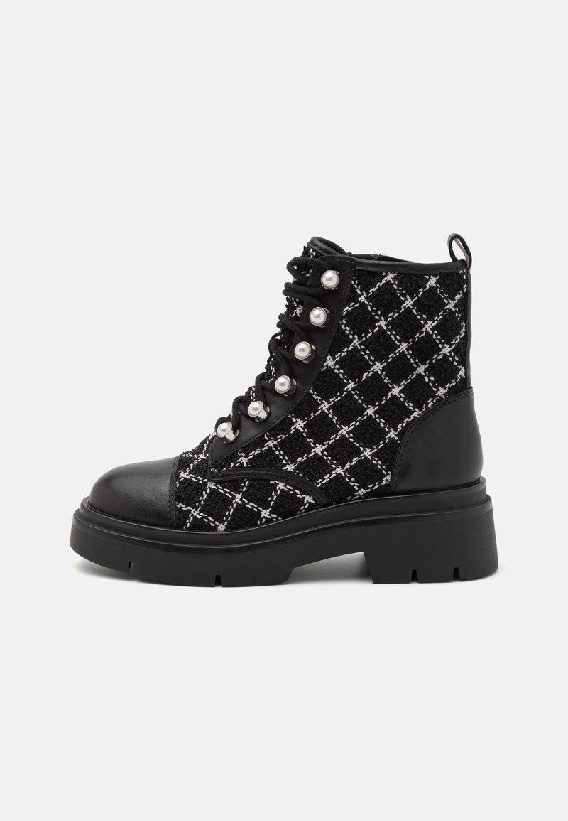 Bottine noire avec motif croisé blanc, crochets à lacets en perles, semelle épaisse, bout en cuir et languette arrière.