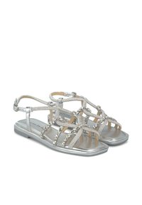 Sandalias planas plateadas con diseño de tiras, adornos decorativos, acabado metálico y textura suave.