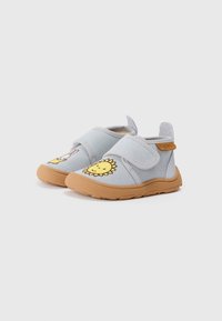 Chaussures en tissu bleu avec une semelle beige, ornées de motifs brodés de soleil et de lapin sur les côtés extérieurs, maintenues par une sangle Velcro.