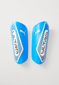 Blue plastic soccer shin guards featuring "ULTRA" branding, orange diagonal stripes, and a white accent. Smooth texture with rounded edges.