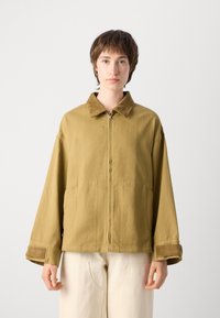 Olive green, oversized jacket with a corduroy collar, front zip closure, two side pockets, and cuffed sleeves. Soft, textured fabric.