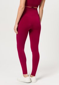 Hoge taille legging in een diepe magenta kleur, gemaakt van zachte, rekbare stof, met een gladde textuur en een aansluitende pasvorm.