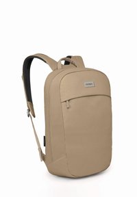 Sac à dos beige avec une surface en tissu lisse, doté d'une poche zippée à l'avant et de bretelles ajustables. Logo OSPREY sur un badge rectangulaire.