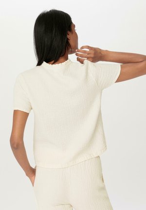 Cremfarbener, kurzärmliger Oberteil aus strukturiertem Stoff. Mit einem fließenden Ausschnitt und einem lockeren Schnitt, der die Rückansicht zeigt.
