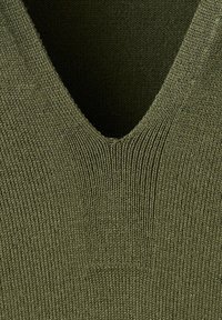 Gros plan sur un tissu tricoté vert olive avec un motif en V et une texture côtelée.