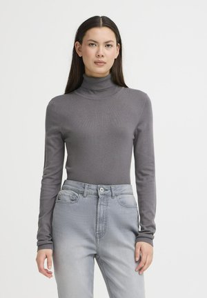 Pilkas ilgas rankovės golfas, pagamintas iš lygios mezginės medžiagos, derinamas su šviesiai pilkomis aukšto liemens džinsais, turinčiais priekines kišenes ir užsegimą mygtuku.