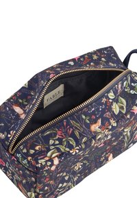 Beauty case in tessuto blu scuro con motivo floreale, dotato di zip dorata e fodera interna nera. Forma compatta e rettangolare con manico laterale.