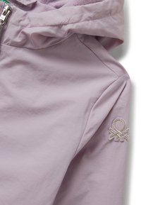 Veste violet claire avec capuche, fermeture éclair et patch logo brodé sur la manche supérieure.