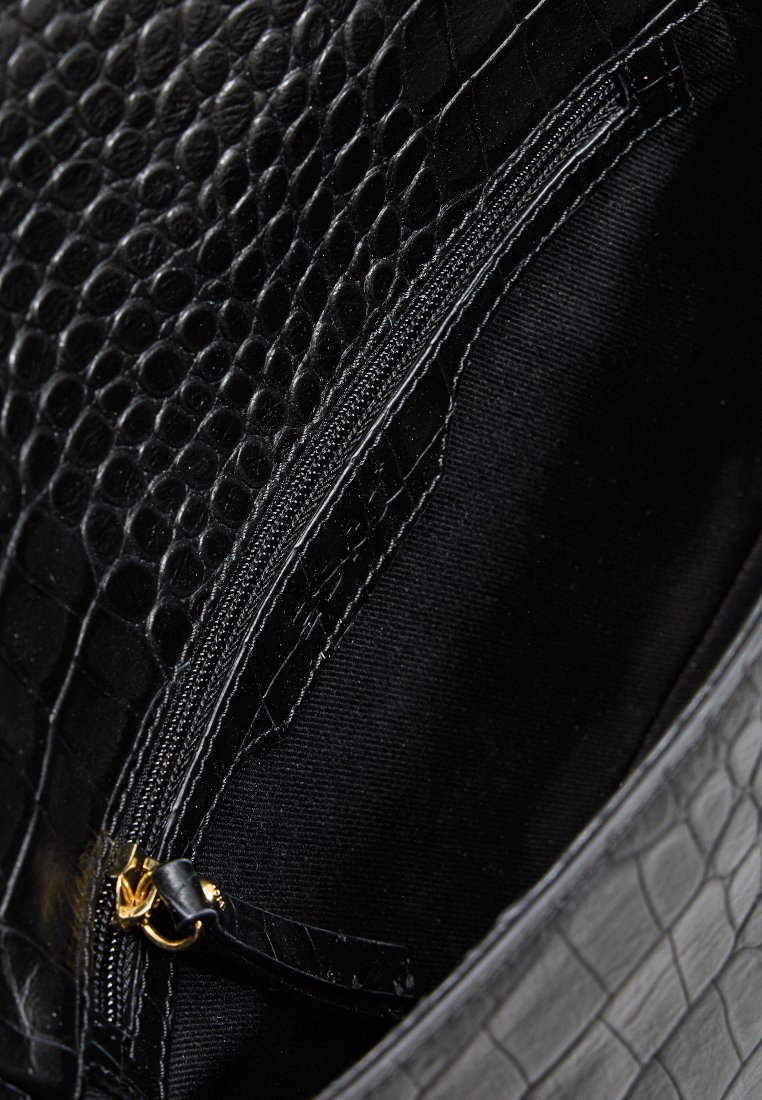 Interno della borsa nero con texture a coccodrillo e tasca con zip. Il tessuto è morbido e opaco, con una cerniera dorata e foderato.