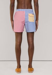 Costumi da bagno con un design a righe in rosso e blu, con una tasca gialla sul lato destro. Vita elastica, tessuto leggero.