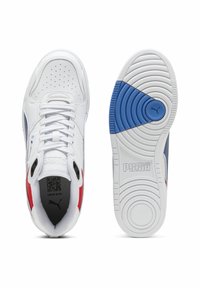 Weiße Puma-Sneaker mit roten und blauen Akzenten, Draufsicht, die Schnürsenkel und Belüftungsöffnungen zeigt, sowie die Sohle mit blauem Griff und Puma-Logo.