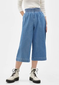 Blå denim culotter med elastisk midja, beskuren längd och uppvikt fåll. Matchas med vita snörade kängor.