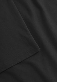 Czarna bawełniana tkanina o gładkiej fakturze i lekkim połysku; posiada podwinięty brzeg oraz widoczne detale szycia.