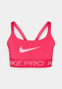 Ružičasti sportski grudnjak izrađen od elastičnog materijala. Ima bijeli Nike logo i rebrasti pojas s natpisom "NIKE PRO" ispisanim velikim slovima. Podesive naramenice.
