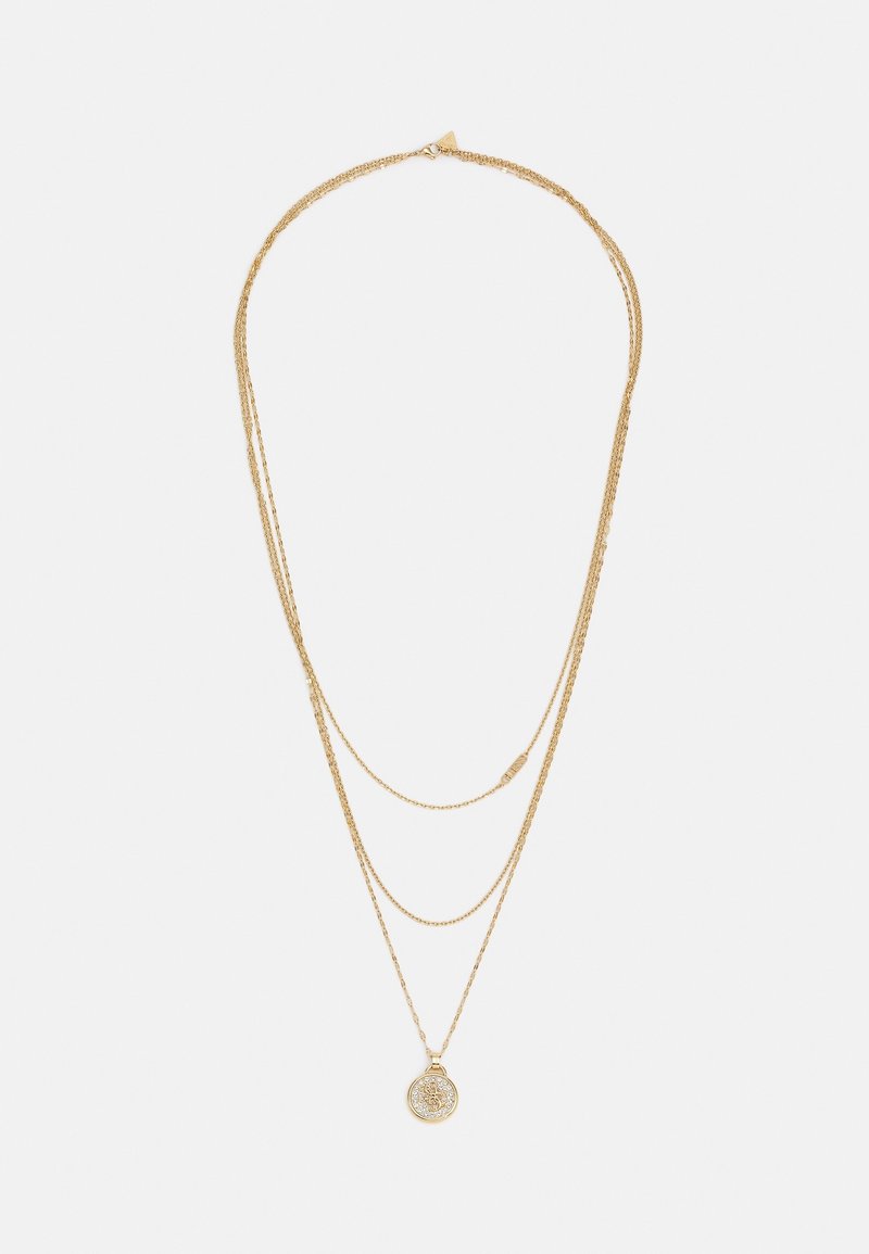 Collier superposé en or avec trois chaînes fines, dont une ornée d'un pendentif rond à motif floral complexe.