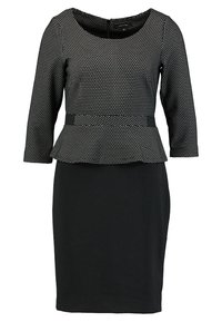 Sorte kjole med trekvartærmer, prikket mønster på toppen, peplum liv og tætsiddende nederdel. Glat stoftekstur gennem hele kjolen.