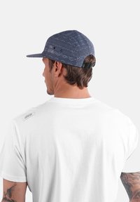 Casquette à motif marine avec une visière plate, en tissu, dotée d'une sangle noire réglable à l'arrière. Portée par une personne en t-shirt blanc.
