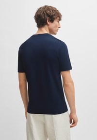 Mørkeblå kortermet t-skjorte laget av glatt stoff, med klassisk rund hals og rett søm, med minimal detaljer på baksiden.