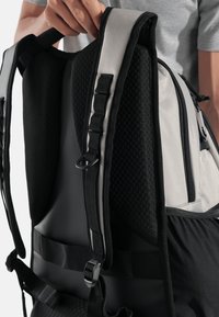 Schwarzer und grauer Rucksack mit gepolsterten Mesh-Trägern, Reißverschlusstaschen, verstellbaren Schnallen und strukturierter Oberfläche. Verfügt über ein schlankes, modernes Design.