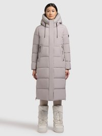 Svetlosivo podložen dolg plašč z visokim ovratnikom, dvema sprednjima žepoma, nastavljivimi vrvico in detajli z zadrgo. Kombiniran z belimi škornji.