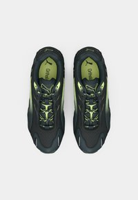 Chaussures de sport noires avec des accents vert fluo. Présentent un matériau en maille, une languette rembourrée et un design à lacets. Semelles texturées pour une meilleure adhérence.