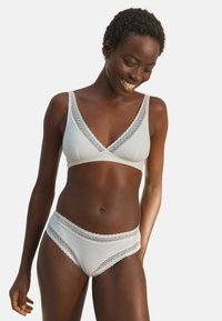 Weißes Baumwoll-Bralette und passende Unterwäsche mit Spitzenrand und V-Ausschnitt-Design. Glatte Textur mit zarten Akzenten entlang der Kanten.