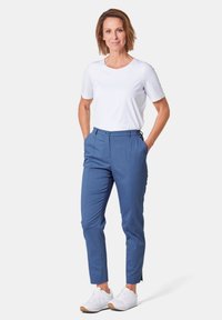 Pantalon bleu sur mesure avec poches latérales, associé à un t-shirt blanc à manches courtes et des baskets blanches ; texture lisse, coupe moderne.