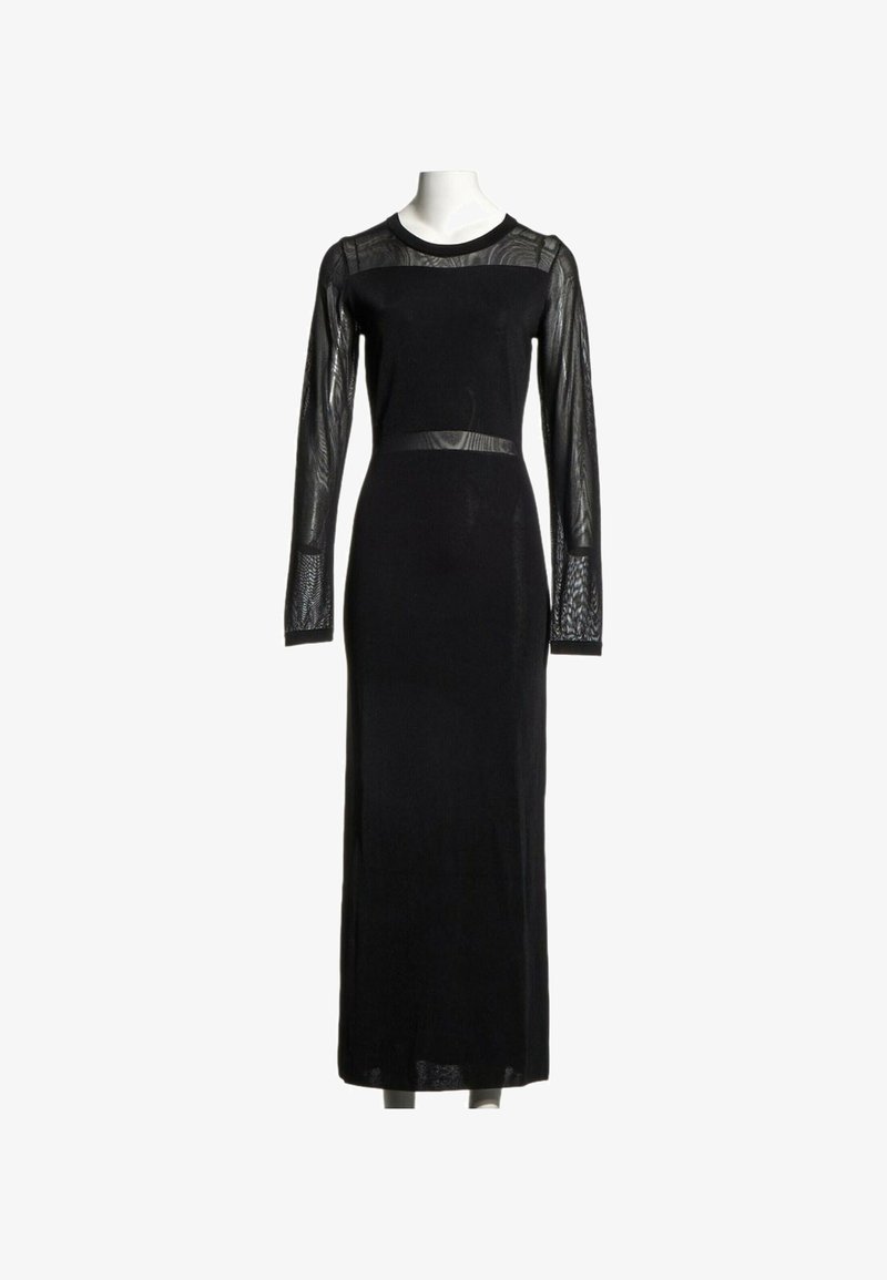 Longue robe noire avec manches longues en maille transparente, empiècement en maille et détail de ceinture en maille sur un mannequin blanc.