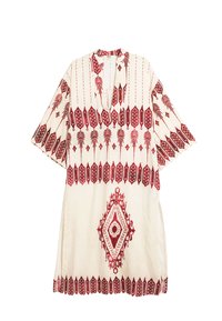 Tunic bianca a maniche corte con ricami geometrici e floreali rossi, caratterizzata da un colletto a V e spacchi laterali per facilitare i movimenti.