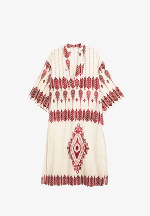 Biała tunika z krótkim rękawem, zdobiona czerwonymi geometrycznymi i kwiatowymi haftami, z dekoltem w kształcie litery V oraz bocznymi rozcięciami dla swobody ruchów.