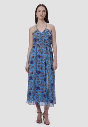 Vestido maxi floral en gasa azul, con cuerpo fruncido y tirantes finos. Presenta vibrantes flores naranjas y moradas, una abertura lateral y un diseño fluido.
