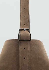 Cinturino in suede marrone con fibbia metallica, caratterizzato da più fori di regolazione e una texture liscia, attaccato a una base più ampia.