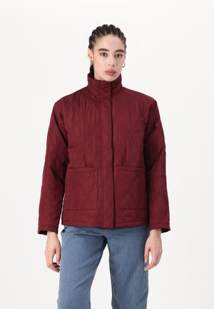 Jachetă matlasată burgund cu guler înalt, mâneci lungi, model în diamant și două buzunare frontale. Asortată cu pantaloni cu dungi.