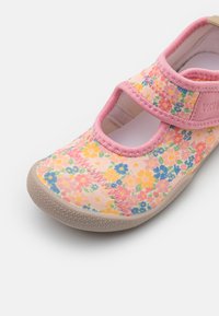 Vaaleanpunaiset ja keltaiset kukkakuosiset lasten kengät, joissa on Mary Jane -design, säädettävä remmi ja beiget kumipohjat.