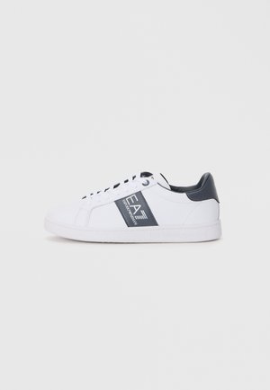 White sneakers with a smooth leather upper, dark grey accents, and a branded side stripe. Round toe and flat rubber sole.