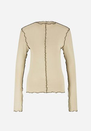 Top beige à manches longues avec un bord festonné, présentant un contour noir contrastant le long des coutures et de l'encolure. Texture lisse.