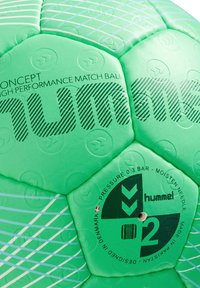 Ballon de soccer vert avec des panneaux hexagonaux texturés, décoré de graphiques noirs et d'un motif rayé blanc, étiqueté "hummel" et spécifications de pression.