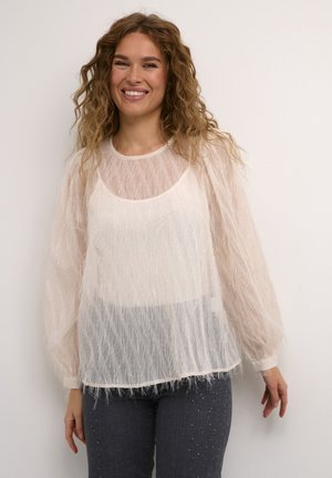 Top bianco trasparente a maniche lunghe con finitura testurizzata e leggera brillantezza, dotato di scollatura tonda e vestibilità ampia, indossato sopra dei denim grigi.