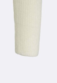 Maglione lavorato a maglia color crema con texture a coste, caratterizzato da maniche a taglio dritto che terminano con un polsino leggermente arrotondato.