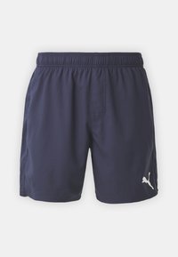 Shorts de bain bleu marine en tissu doux avec une taille élastique. Présente un logo blanc sur le côté gauche à l'avant et une poche latérale.