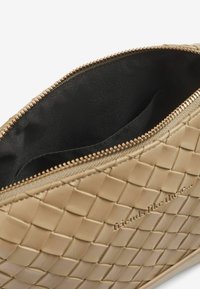 Clutch in pelle intrecciata beige con chiusura a zip, dotato di una fodera interna liscia e testo in rilievo lungo il lato.